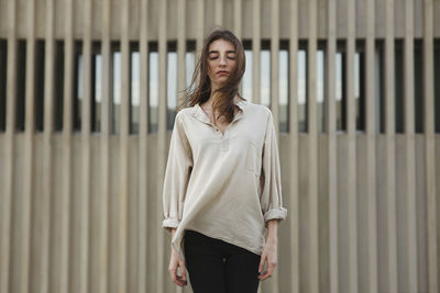 Beautiful young woman standing against wall