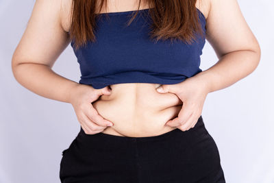 Midsection of woman standing against white background