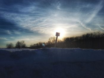 Snow on field against sky during sunset