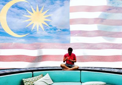 Man sitting against malaysian flag painting