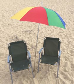 Empty chairs on sand at beach