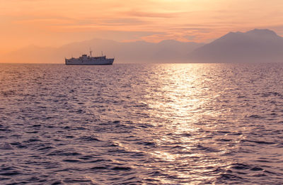 Boat sailing in sea against sky during sunset