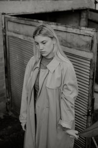 Portrait of a young woman standing against built structure