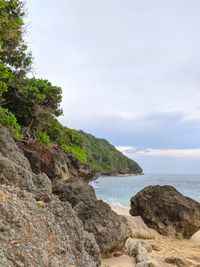 Scenic view of rocks by sea against sky