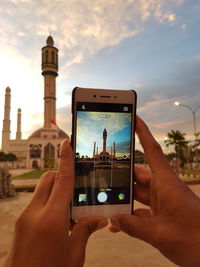 Midsection of man using mobile phone against sky