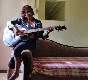 Portrait of man playing guitar at home