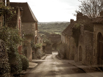 Empty road amidst buildings against sky