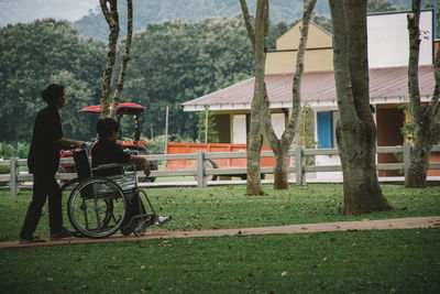 Side view of woman pushing man on wheelchair