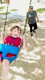 Portrait of happy girl playing on swing at playground