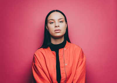 Portrait of confident young woman over pink background