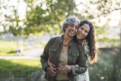 Portrait of smiling mother and daughter standing at park