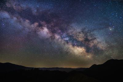 Silhouette mountain against star field at night