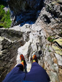 Low section of person on rock by cliff