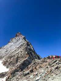 Low angle view of rocky mountain against clear blue sky