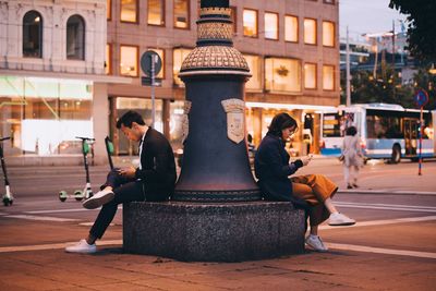 Side view of male and female surfing net while sitting in city during dusk