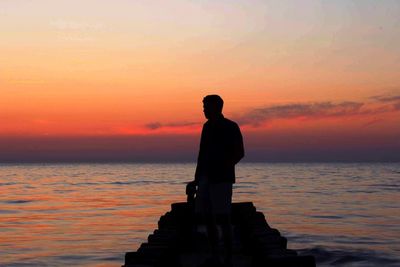 Silhouette of woman on sea during sunset