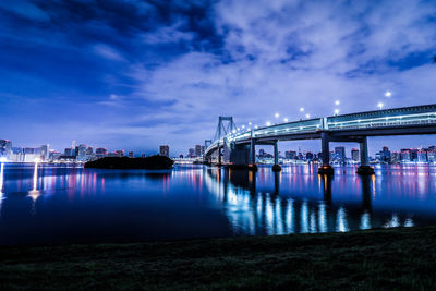 Illuminated bridge over river against sky at night