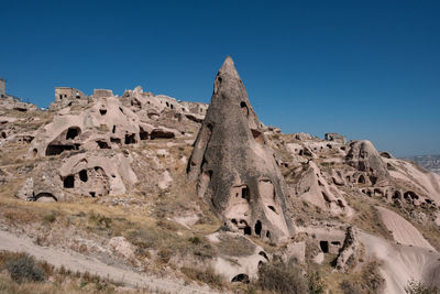 Low angle view of rock formations against clear blue sky