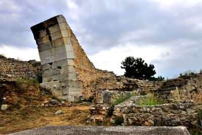 Low angle view of archaeological site against cloudy sky