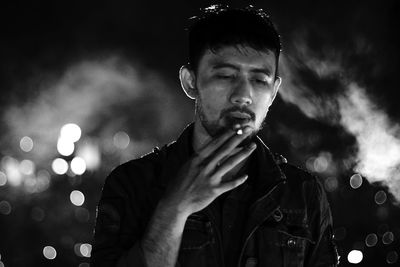 Man smoking cigarette against sky at night