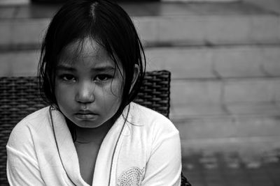 Portrait of girl wearing bathrobe sitting on chair at yard