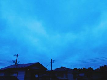 Low angle view of silhouette buildings against blue sky