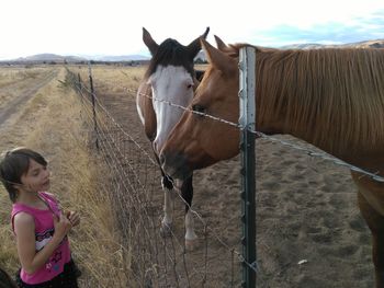 Girl standing by horses on field