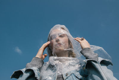 Low angle view of woman with plastic on face against sky