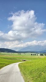 Road amidst field against sky