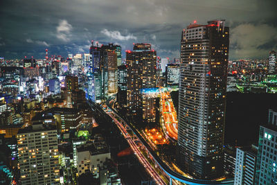 Illuminated modern buildings in city against sky at night