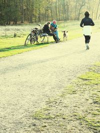 Rear view of people riding bicycle on road