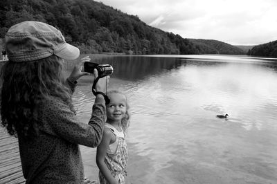 Girl holding camera with sister by lake at plitvice lakes national park