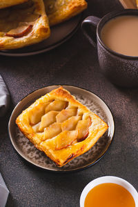 Small upside down puff pastry cake with apple on a plate vertical view