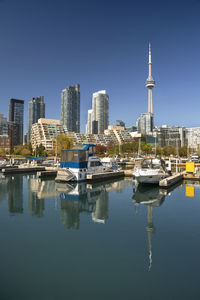 Sailboats moored in city by buildings against clear sky