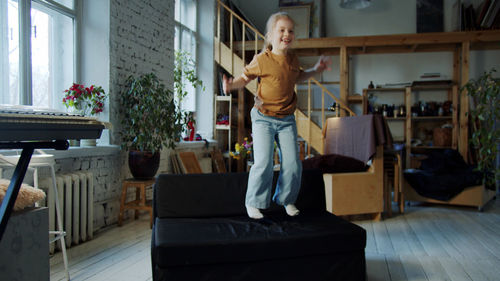 Cute girl jumping on sofa at home