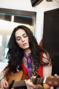 Young woman playing acoustic guitar at a recording studio