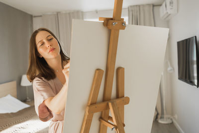 Portrait of young woman sitting on bed at home