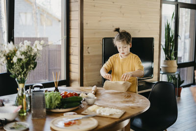 Playful boy's face covered with flour preparing dough at home