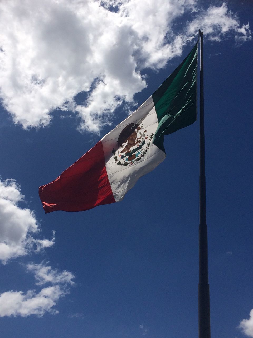 low angle view, flag, identity, sky, cloud, wind, fluttering, national flag, flag pole, pole, cloud - sky, day, outdoors, no people, symbol, red