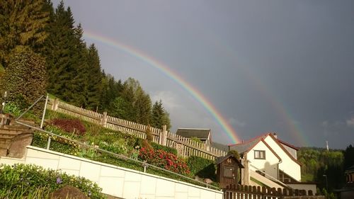 Low angle view of rainbow over buildings against sky