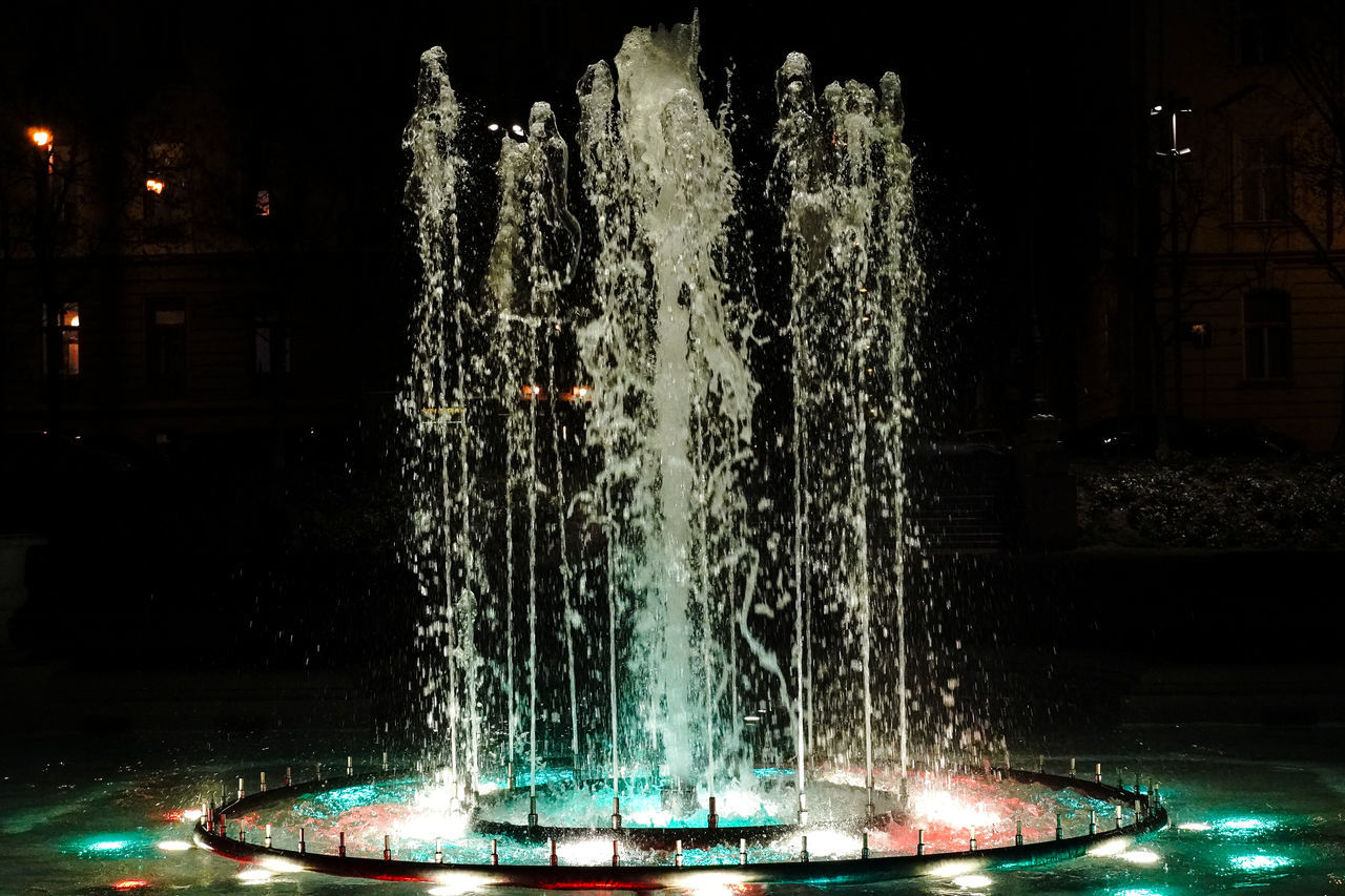 ILLUMINATED WATER FOUNTAIN IN CITY AT NIGHT