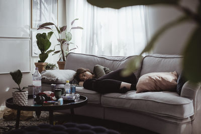 Worried young woman lying on sofa at home