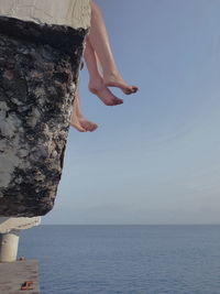 Woman on rock by sea against sky