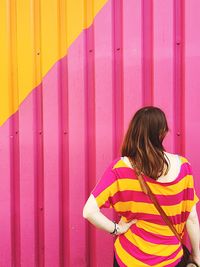 Rear view of young woman standing in front of corrugated iron