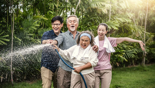 Cheerful family enjoying while holding water pipe at park