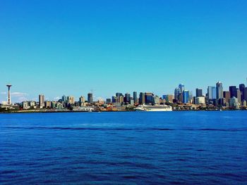 Scenic view of river against clear blue sky in city