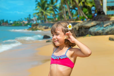Girl holding seashell at beach on sunny day