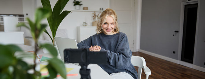 Portrait of young woman sitting on chair at home