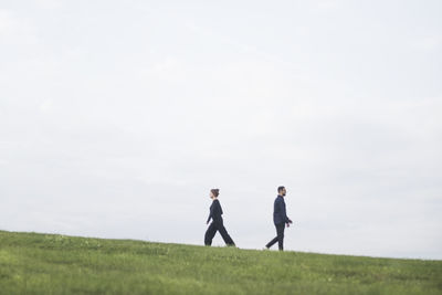 Men standing on field against sky