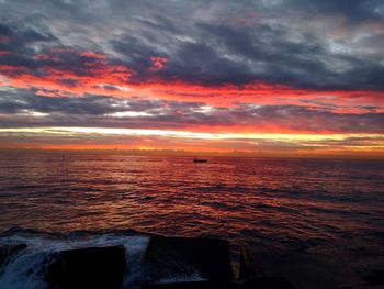 Scenic view of sea against dramatic sky during sunset